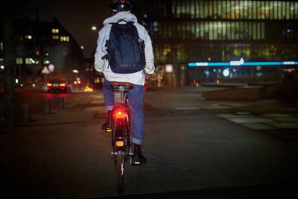 picture of man riding bicycle with a ebike light in the back shining bright