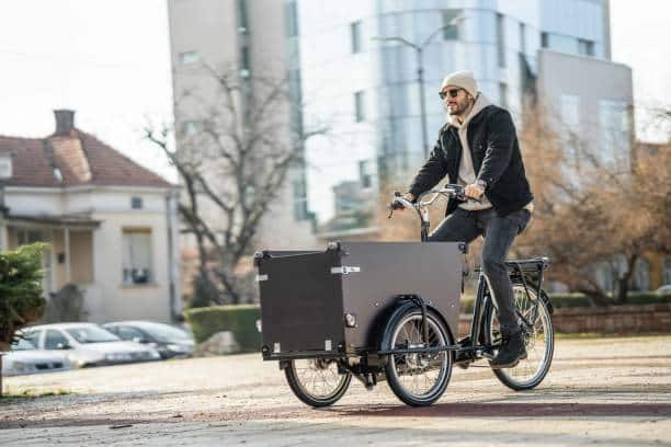 Handsome young hipster man riding his cargo bike in the city