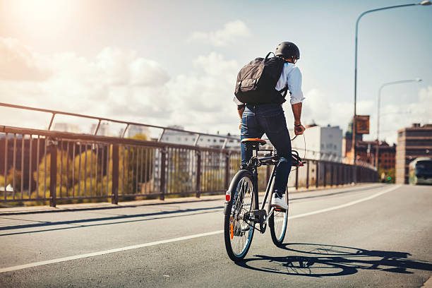 man with backpack riding an e-bike on the road