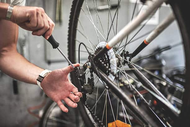 Close up shot of male hands fixing the gearshift mechanism on rear bicycle wheel.