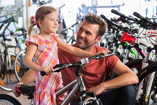 Father buying a bicycle for his little daughter in a bike store.