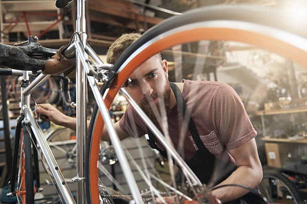 Shot of a handsome young bicycle mechanic working on a customer's bicycle