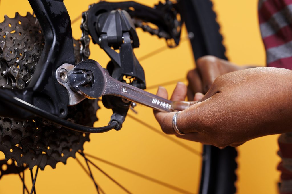 Photo focus on person holding specialized tool for repairs and maintenance of broken bicycle. Close up view of african american hands adjusting various components with precision and expertise.