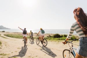 Photo of a smiling teenage girls, using bicycles to commute to the beach