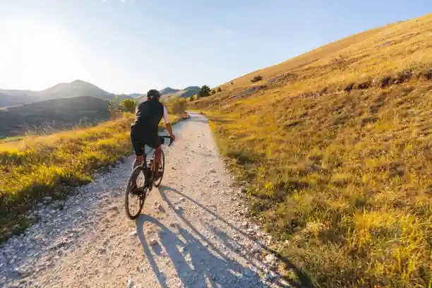Amazing view of a cyclist with gravel bike pedaling a country road at sunset, Apennines, Italy