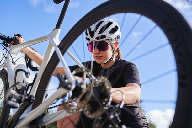 Female cyclist inspecting and adjusting her bike on a sunny day, Focused cyclist performing bike maintenance