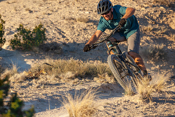 Mature man mountain bikes trail on extreme desert badlands landscape terrain. Such beautiful nature scenery and outdoor sports and wellness can found while riding the White Ridge trails of central New Mexico