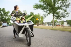 woman riding on cargo bike with her 2 kids